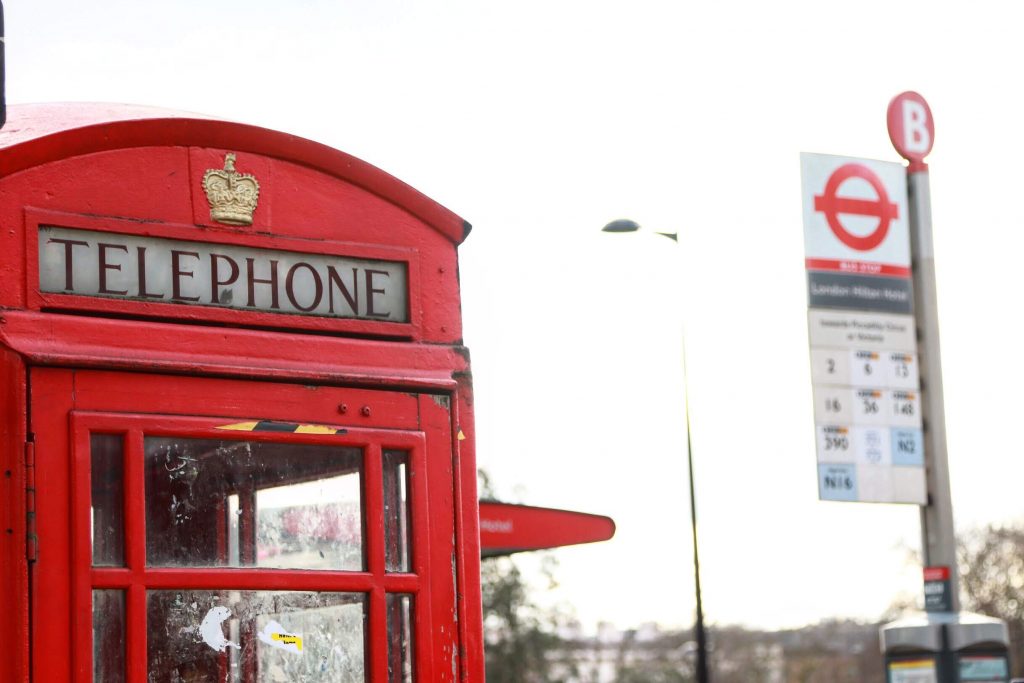 cabine telefônica vermelha de Londres com parada de ônibus desfocada ao lado
