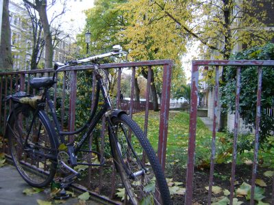 bicicleta antiga amarrada num portão de ferro em um parque