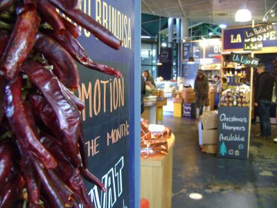 : Mercado coberto com bancas de alimentos e pimentas secas penduradas.