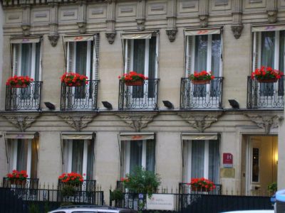 Prédio clássico com flores vermelhas na fachada em Paris