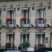 Prédio clássico com flores vermelhas na fachada em Paris