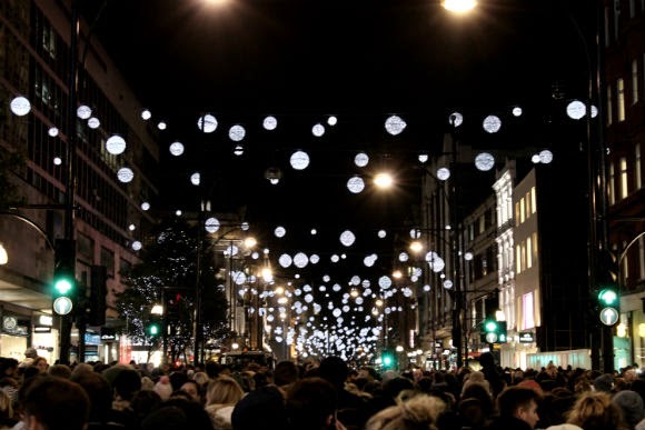 Multidão caminhando sob luzes de Natal na Oxford Street em Londres à noite