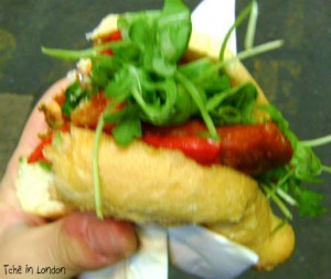 Sanduíche de rua em Londres com linguiça, pimentão e rúcula.