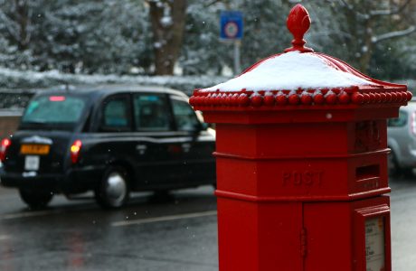 taxi preto londrino com caixa de correio bvermelha em um dia de neve