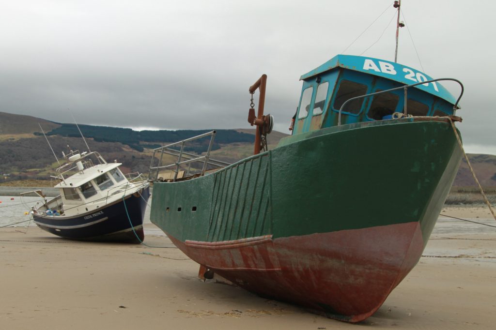 barco verde abandonado na margem da praia de barmouth no pais de gales