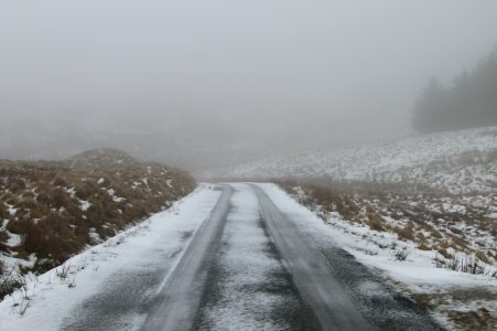 estrada com neve e marcas de roda no interior do pais de gales, snowdonia.