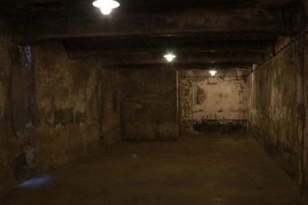Câmara de gás de Auschwitz I (Crematorium I). Câmara ed tijolo com três luzes baixas e marcas nas paredes