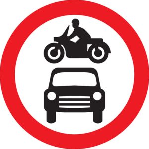 Placa de trânsito britânica em Londres indicando “proibido veículos motorizados”, com ícone de motocicleta e carro dentro de um círculo vermelho.