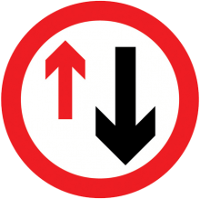 Placa de trânsito circular com borda vermelha, seta preta para baixo e seta vermelha para cima, indicando “preferência ao sentido contrário” ou “via com prioridade para veículos que vêm em sentido oposto”.