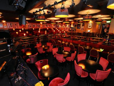 Ronnie Scott's clube de jazz com iluminação baixa e cadeiras vermelhas