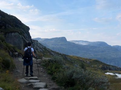 homem guri in london fazendo hiking com vista pra montanhas na trilha trolltunga na noruega