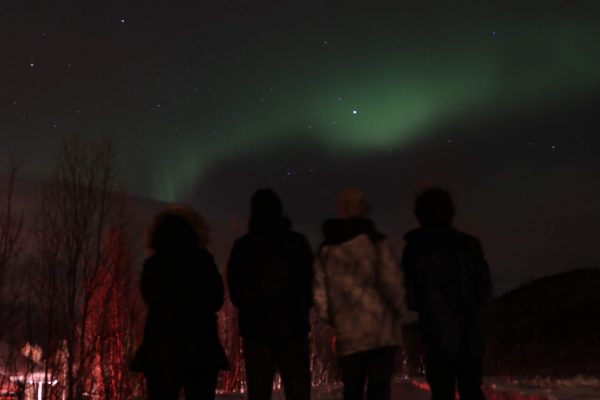 quatro pessoas vendo a aurora boreal no norte da noruega