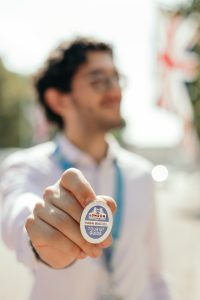 Guia turístico mostrando credencial oficial de turismo em Londres, com bandeira britânica ao fundo.