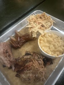 brisket desfiado com carne de porco desfiada com salsicha de porco, coleslaw e Mac n' cheese, servidos numa bandeja de metal
