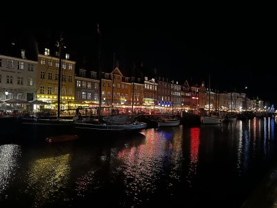 Prédios coloridos do antigo porto de Copenhagen iluminados à noite e refletidos no canal