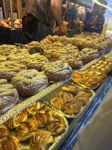 Pães e itens de confeitaria expostos em uma vitrine com coloração mais quente. Doces com pistache, canela, açúcar e cardamomo na vitrine de padaria em Copenhagen.