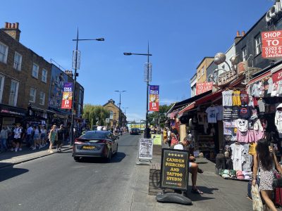 Pessoas caminhando em barracas de venda em Camden Town com céu azul em Londres