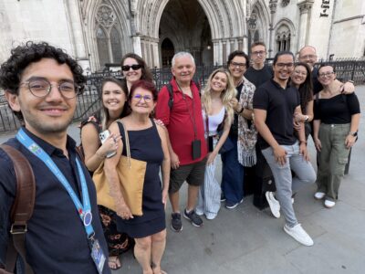 Grupo de pessoas sorrindo com guia de turismo Blue Badge em frente a prédio famoso em Londres